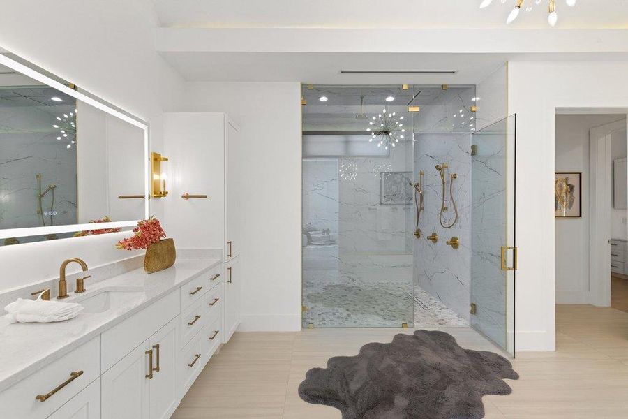 A well-lit primary bathroom featuring a spacious vanity with ample storage and a modern glass-enclosed shower.