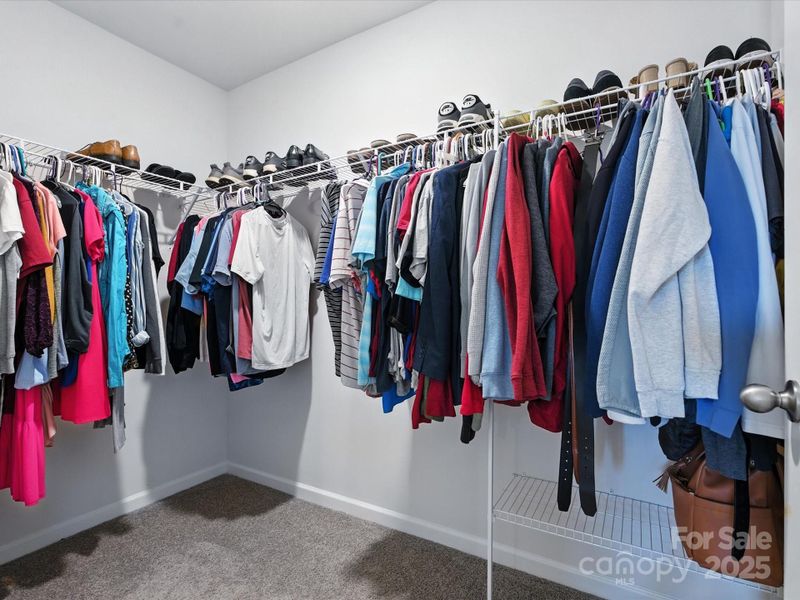 Generous walk-in closet with wire shelving systems providing ample storage for clothing and accessories. Carpet flooring and organized layout maximize storage efficiency in the primary suite.