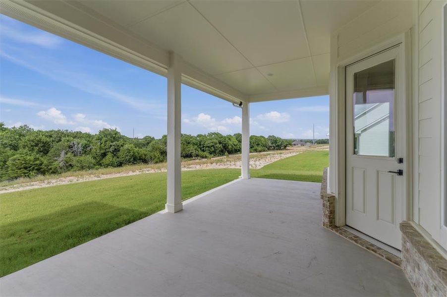 Covered concrete patio with white columns and a clear sky backdrop Covered concrete patio with white columns and a clear sky backdrop