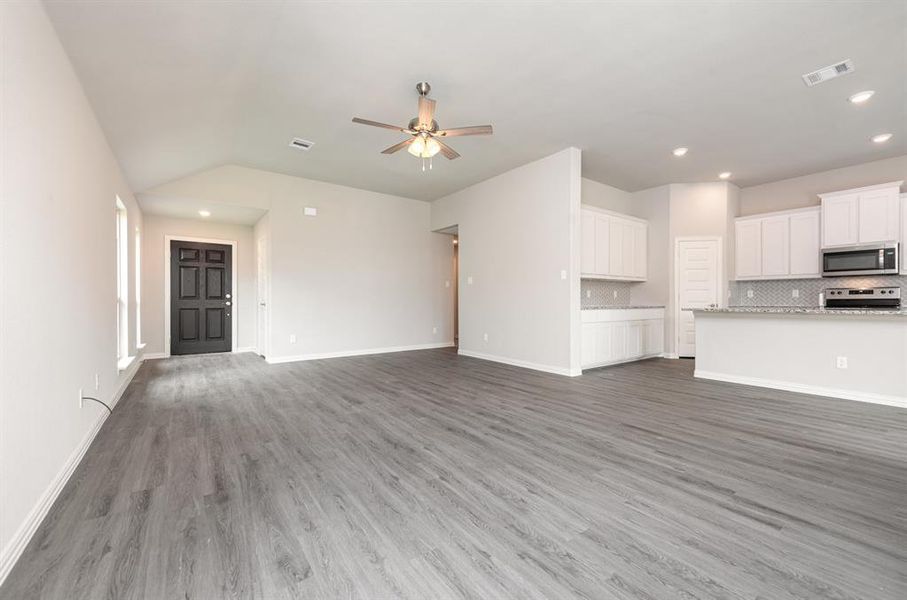 Unfurnished living room featuring ceiling fan, hardwood / wood-style flooring, and lofted ceiling