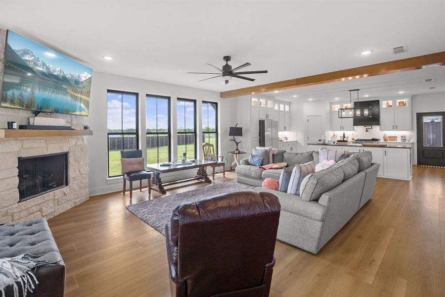 Living area featuring ceiling fan, a stone fireplace, recessed lighting, and light wood-style flooring Living area featuring ceiling fan, a stone fireplace, recessed lighting, and light wood-style flooring