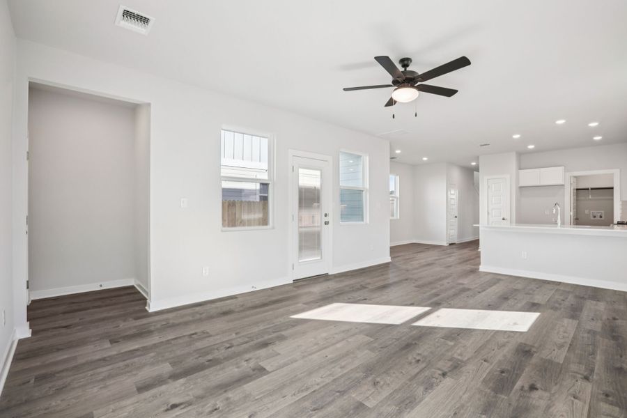 A room with white walls and a wood floor with a fan.