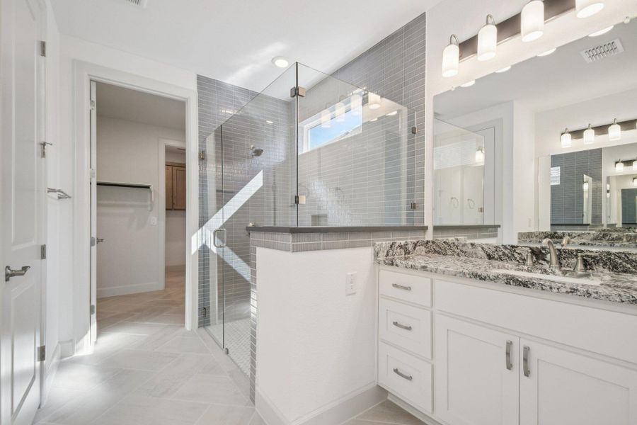 Full bathroom featuring a spacious closet, vanity, a stall shower, and light tile patterned floors Full bathroom featuring a spacious closet, vanity, a stall shower, and light tile patterned floors