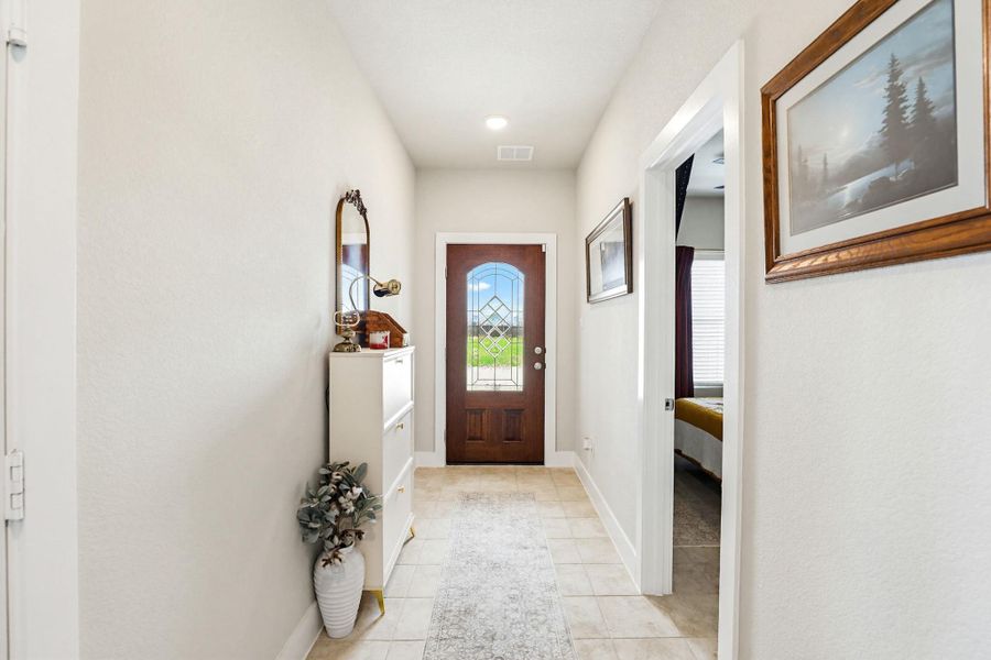 Entryway featuring a weather proof door with leaded glass, light-toned tile flooring, and white walls