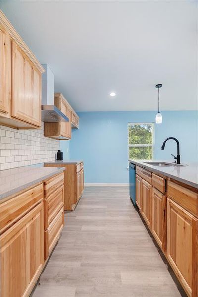 Kitchen with light stone countertops, light brown cabinets, tasteful backsplash, and recessed lighting Kitchen with light stone countertops, light brown cabinets, tasteful backsplash, and recessed lighting