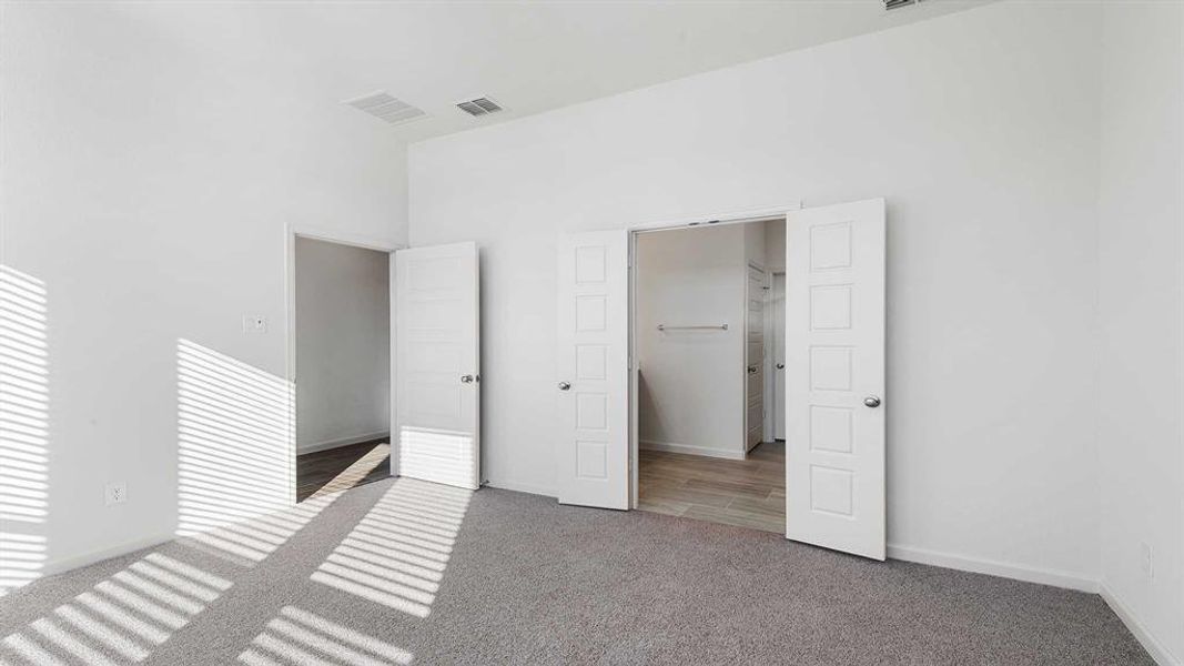 Unfurnished bedroom with carpet and a towering ceiling