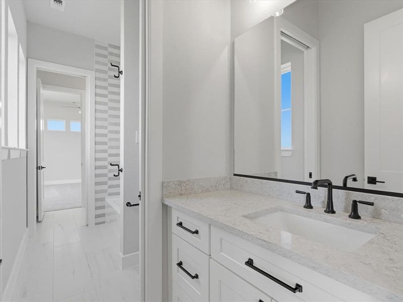 Bathroom vanity featuring a light-toned countertop, integrated sink, and matte black hardware