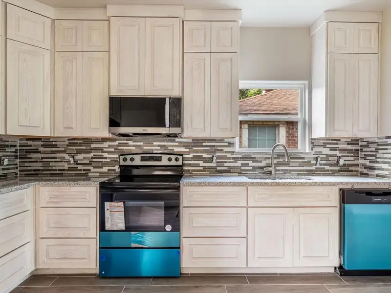 Kitchen featuring appliances with stainless steel finishes, backsplash, wood finish floors, and light stone countertops Kitchen featuring appliances with stainless steel finishes, backsplash, wood finish floors, and light stone countertops