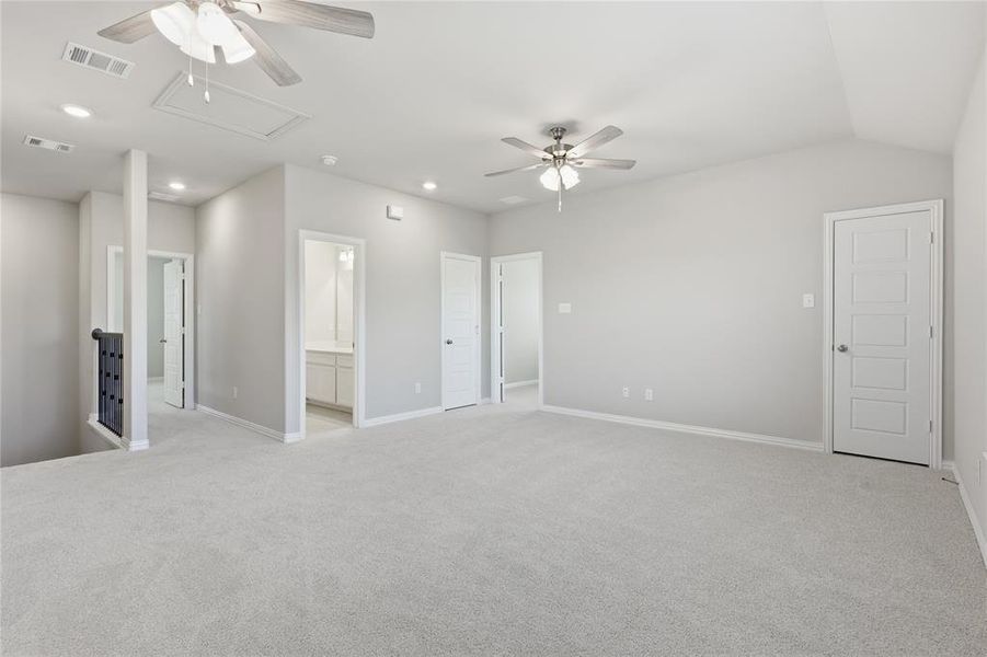 Expansive carpeted loft space featuring vaulted ceilings, recessed lighting, and two ceiling fans