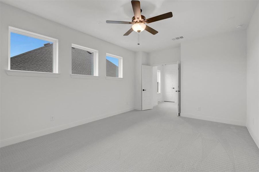 This room features soft gray carpet, white walls, and a ceiling fan with a light fixture
