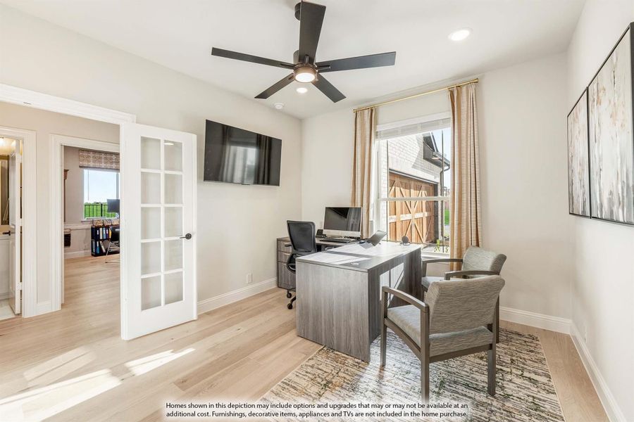 Home office with gray desk, ceiling fan, wall-mounted TV, and French doors on light hardwood floors