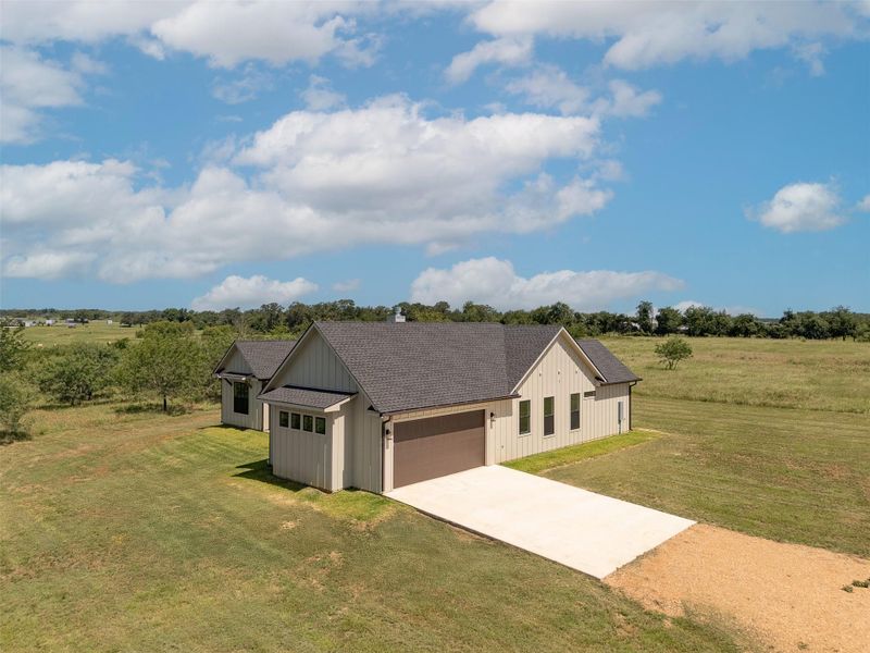 Rear view of house with a yard, a chimney, a patio, a garage, and concrete driveway