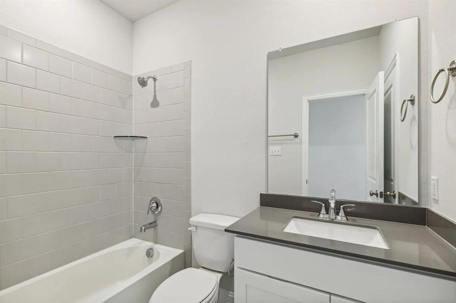 Full bathroom featuring tiled shower / bath combo, toilet, and vanity