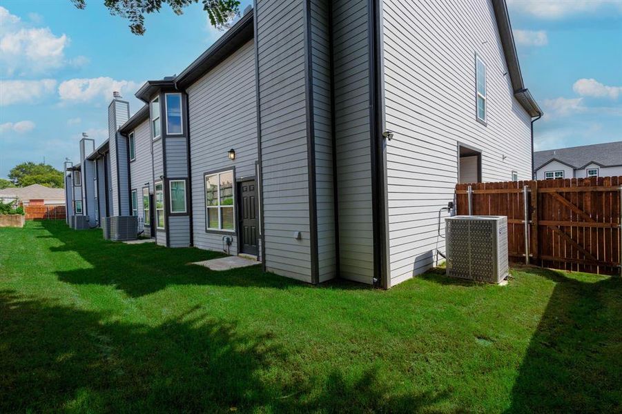 Back of property featuring central air condition unit and a yard