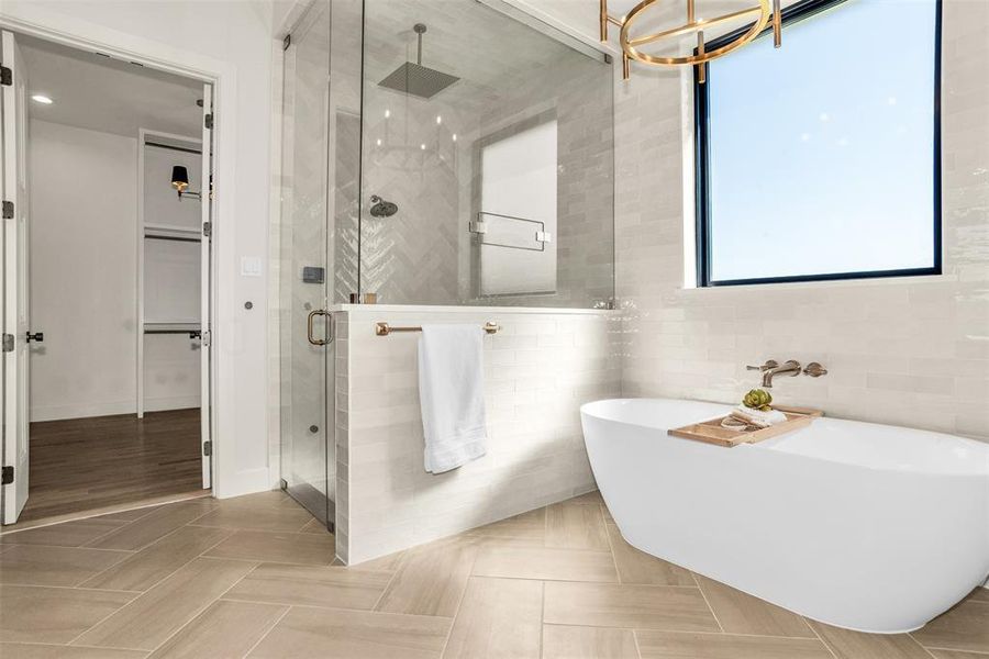 Bathroom featuring a stall shower, a freestanding tub, tile walls, and a spacious closet Bathroom featuring a stall shower, a freestanding tub, tile walls, and a spacious closet
