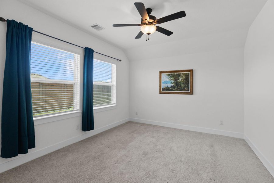 Great view of the primary bedroom with nice big windows for natural light and ceiling fan.