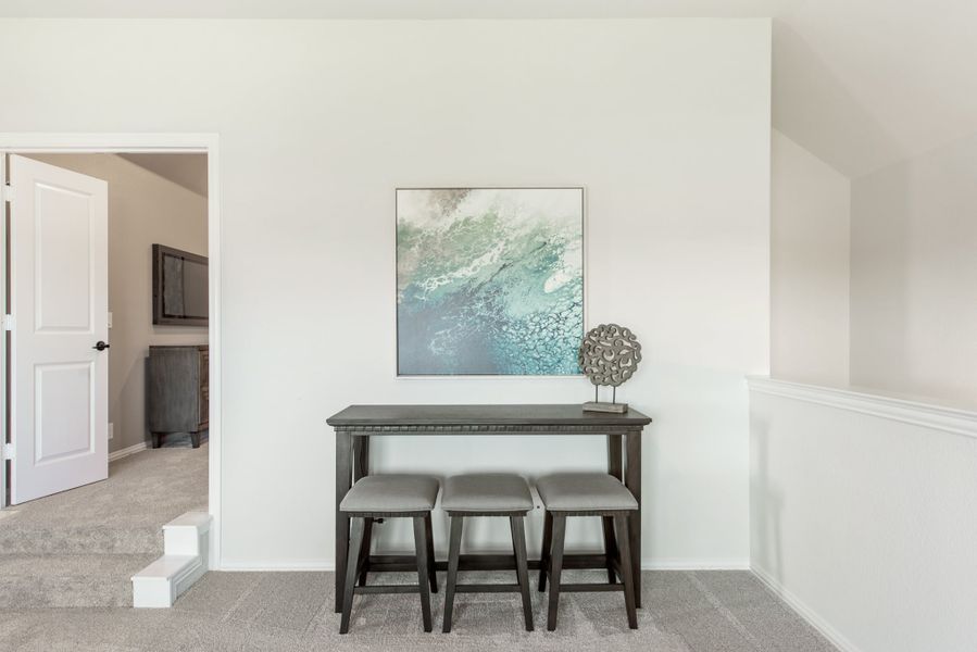 Upstairs hallway landing with dark console table, three gray stools, and abstract wall art above