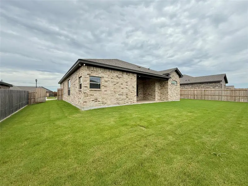 Back of property with a fenced backyard, brick siding, a patio, and roof with shingles Back of property with a fenced backyard, brick siding, a patio, and roof with shingles