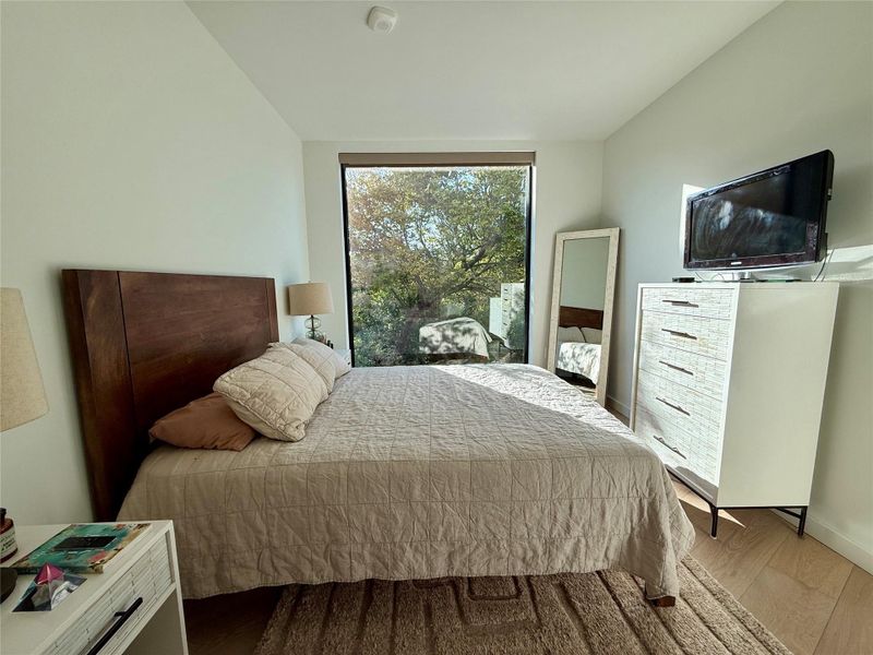 Floor-to-ceiling window brings nature views into this serene bedroom.