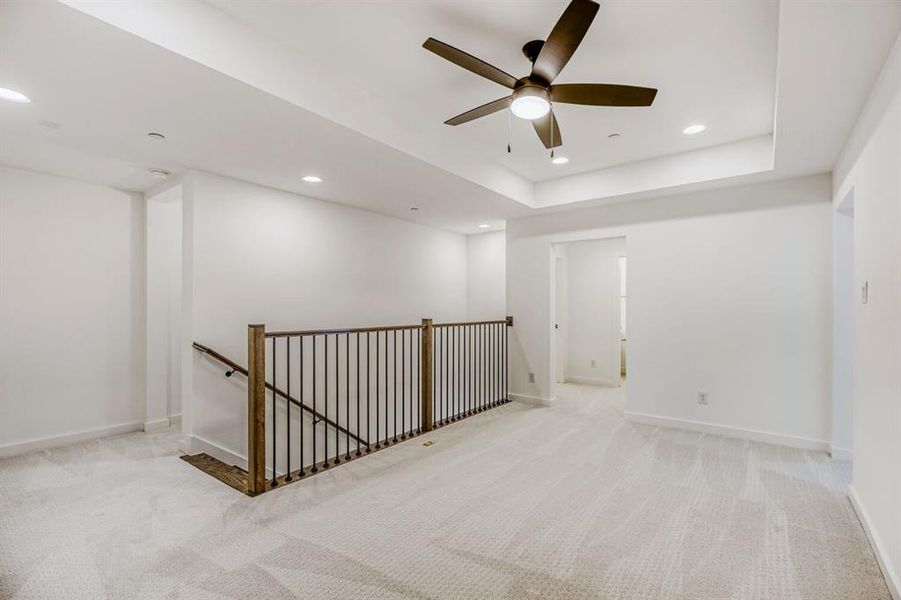 Spare room featuring light carpet, recessed lighting, ceiling fan, and a tray ceiling