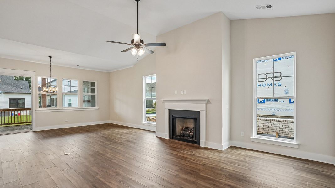 Open Concept layout living room with fireplace and vaulted ceiling, with view of screened in porch
