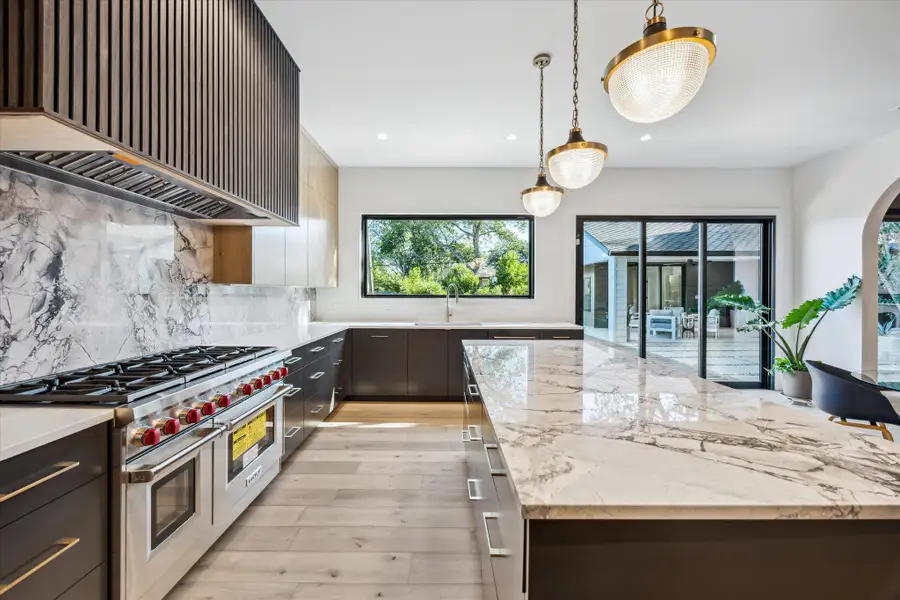Kitchen with Wolf range with two ovens, custom range hood, a kitchen island, & huge window on sink wall Kitchen with Wolf range with two ovens, custom range hood, a kitchen island, & huge window on sink wall