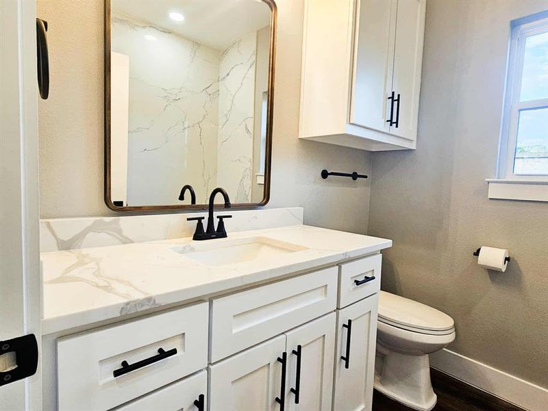 Guest bath with quartz countertops and backsplash in shower, custom cabinets, and shower/tub combo.