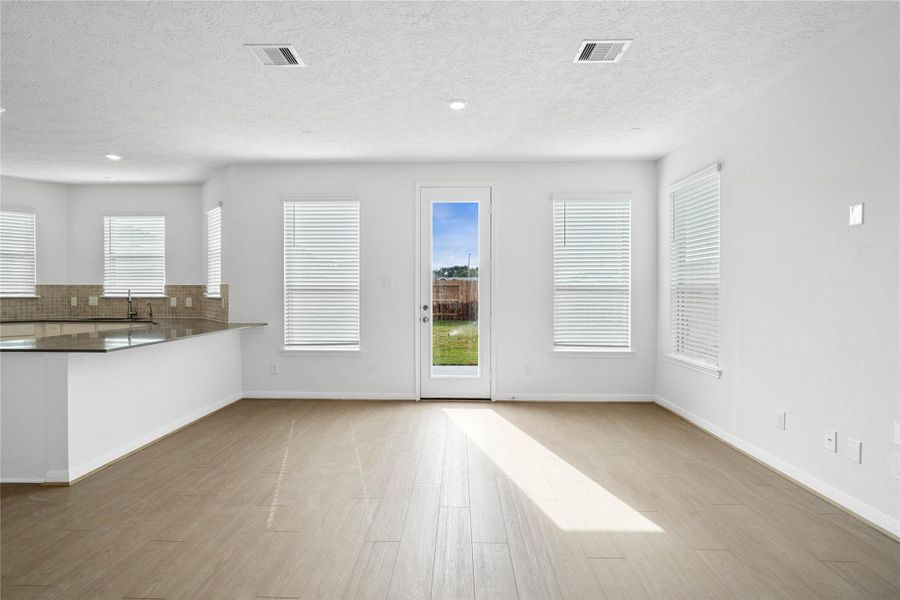 Create lasting memories around the table with family and friends in this inviting dining room! It showcases high ceilings, large windows with privacy blinds, access door to the back patio and yard, vinyl plank flooring, and recessed lighting for a warm and welcoming atmosphere.