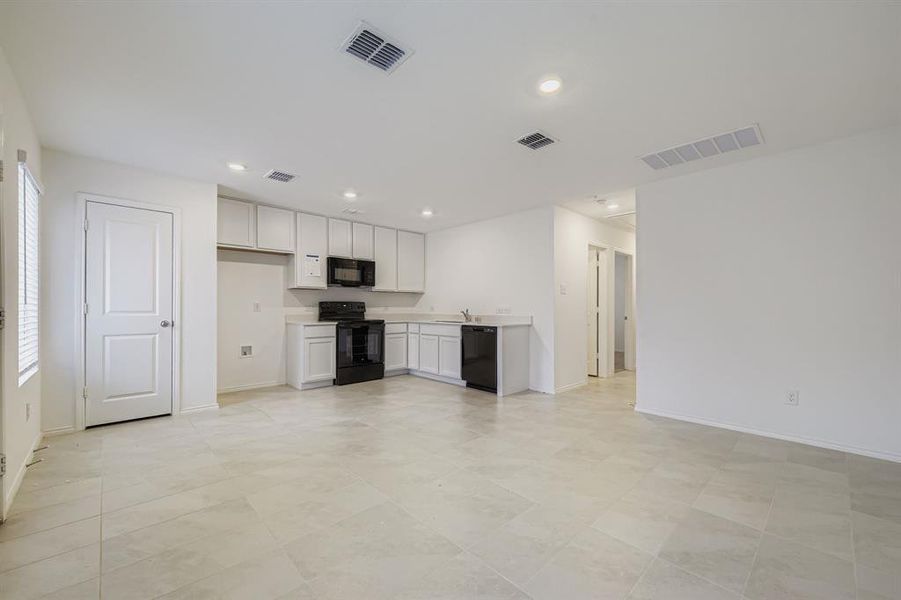 Kitchen featuring light countertops, white cabinets, black appliances, recessed lighting, and open floor plan