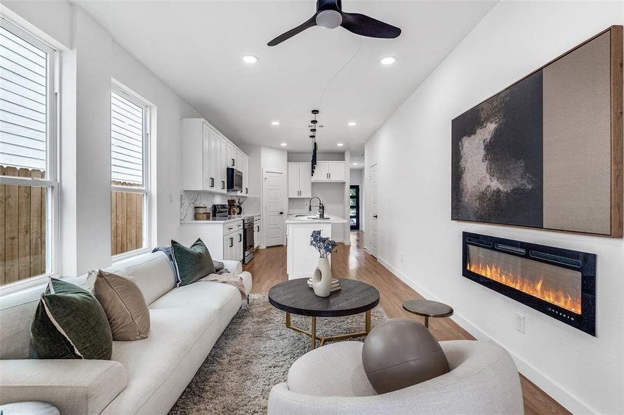 Living room featuring a glass covered fireplace, recessed lighting, light wood-type flooring, and ceiling fan Living room featuring a glass covered fireplace, recessed lighting, light wood-type flooring, and ceiling fan