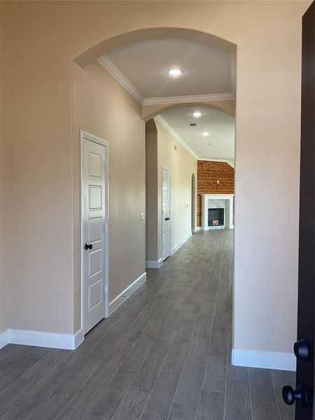 Corridor with ornamental molding, dark wood-style floors, arched walkways, and recessed lighting Corridor with ornamental molding, dark wood-style floors, arched walkways, and recessed lighting