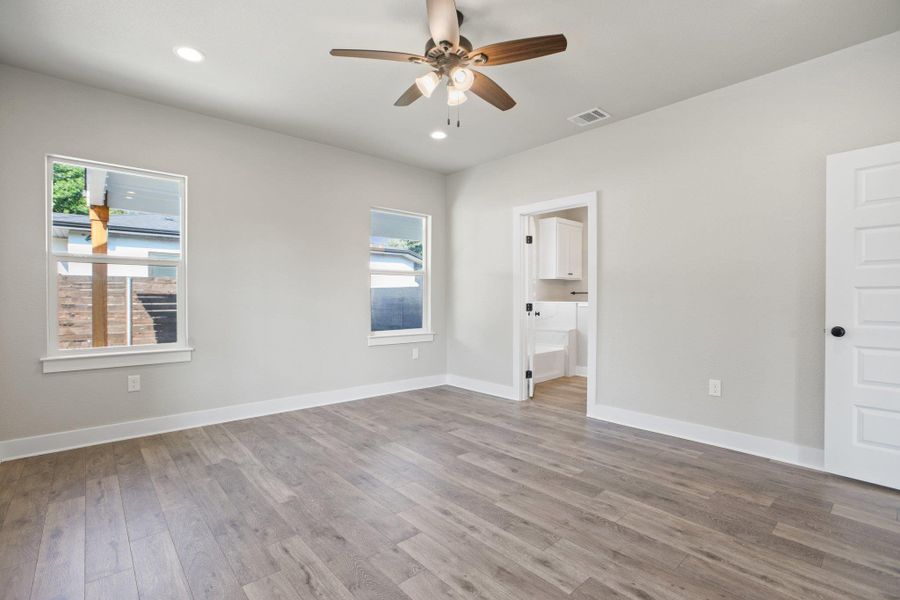 Unfurnished bedroom featuring wood finished floors, a ceiling fan, recessed lighting, and ensuite bath