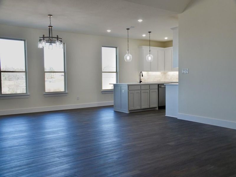 Kitchen featuring dishwasher, sink, hanging light fixtures, dark hardwood / wood-style floors, and white cabinets