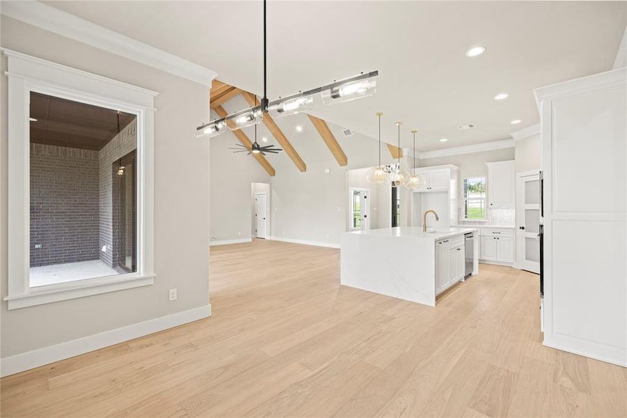 Kitchen featuring open floor plan, a chandelier, decorative light fixtures, white cabinetry, and light wood-type flooring Kitchen featuring open floor plan, a chandelier, decorative light fixtures, white cabinetry, and light wood-type flooring