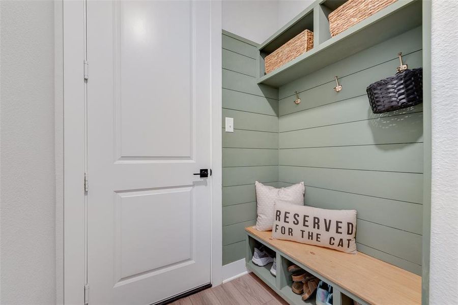 Entryway mudroom featuring shiplap accent wall, built-in bench with storage cubbies, and integrated shelving with brass hooks