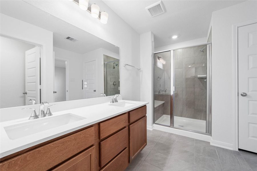This beautifully updated primary bathroom is move-in ready! It showcases stained cabinetry paired with light countertops, dual vanity sinks, a large mirror, a spacious walk-in shower with tile surround and seat, high ceilings, custom paint, and stylish modern finishes throughout. This beautifully updated primary bathroom is move-in ready! It showcases stained cabinetry paired with light countertops, dual vanity sinks, a large mirror, a spacious walk-in shower with tile surround and seat, high ceilings, custom paint, and stylish modern finishes throughout.