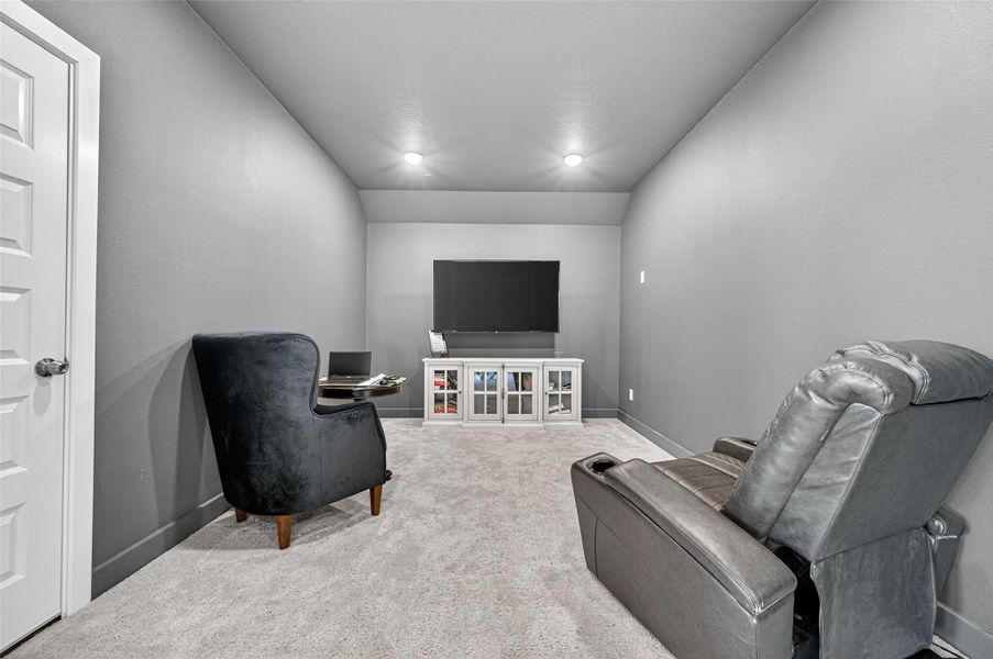 Cozy media room with gray walls and carpet, featuring a large TV, comfortable recliner, and armchair, ideal for entertainment or relaxation. Cozy media room with gray walls and carpet, featuring a large TV, comfortable recliner, and armchair, ideal for entertainment or relaxation.
