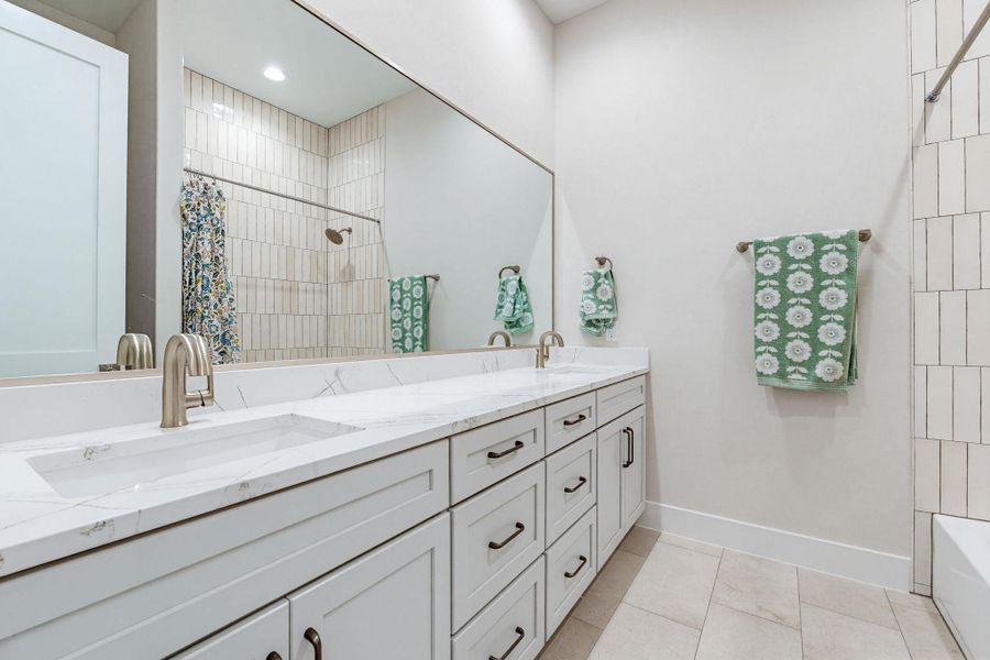Double vanity with stone counters provides ample space and sleek design in this bathroom.