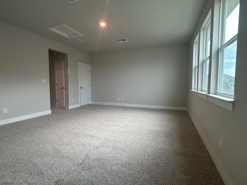 Empty room featuring attic access and light colored carpet