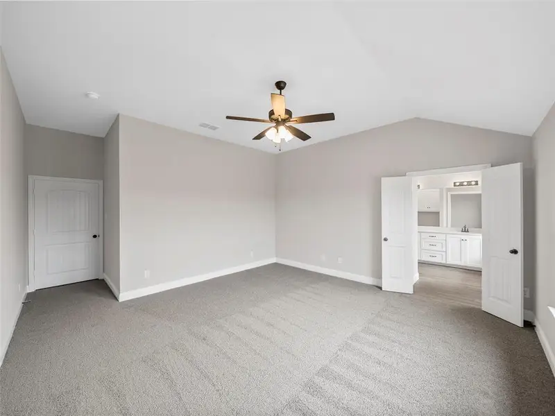 Unfurnished bedroom featuring vaulted ceiling, carpet floors, visible vents, and baseboards