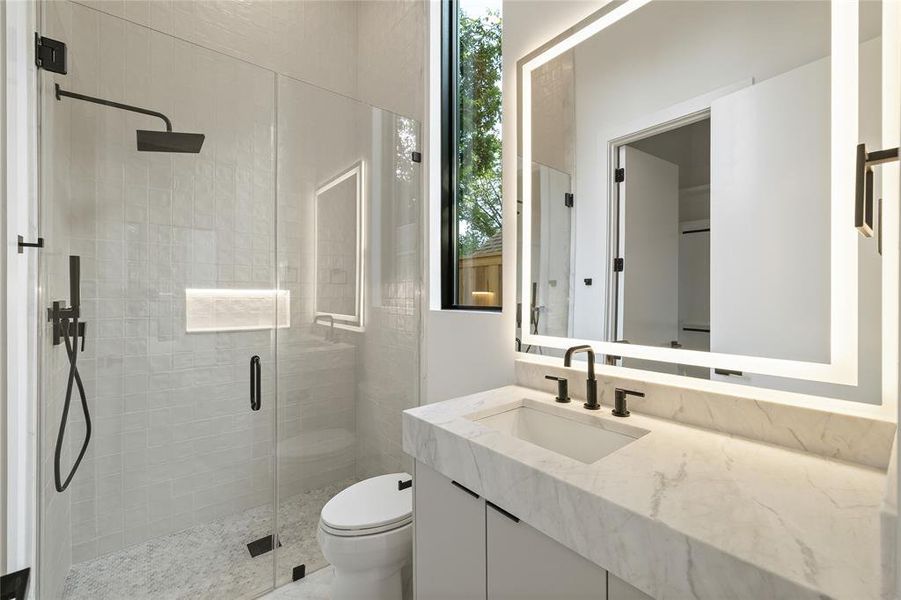 Modern bathroom featuring a frameless glass shower enclosure with matte black fixtures, a built-in shower niche, and a rain shower head Modern bathroom featuring a frameless glass shower enclosure with matte black fixtures, a built-in shower niche, and a rain shower head