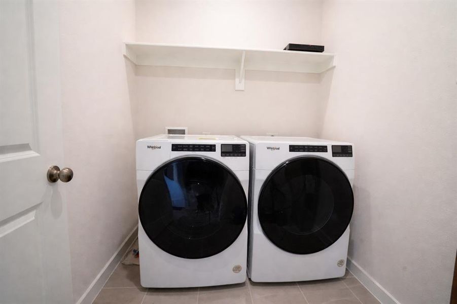Washroom with light tile patterned floors and washer and clothes dryer