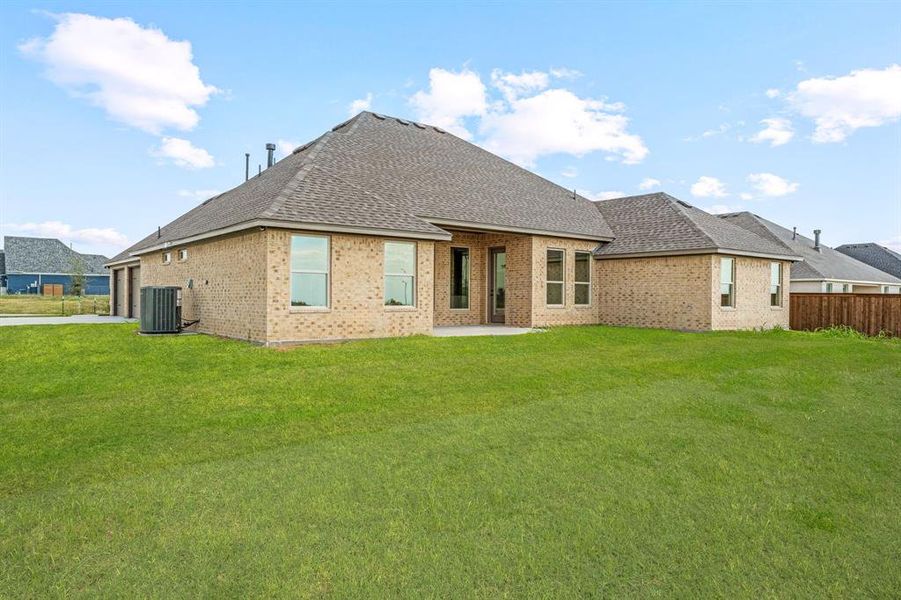 Rear view of house featuring a shingled roof, a patio, and brick siding