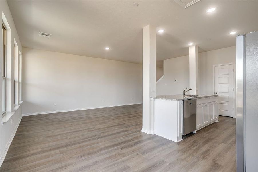 Kitchen with appliances with stainless steel finishes, light stone countertops, an island with sink, white cabinetry, and open floor plan
