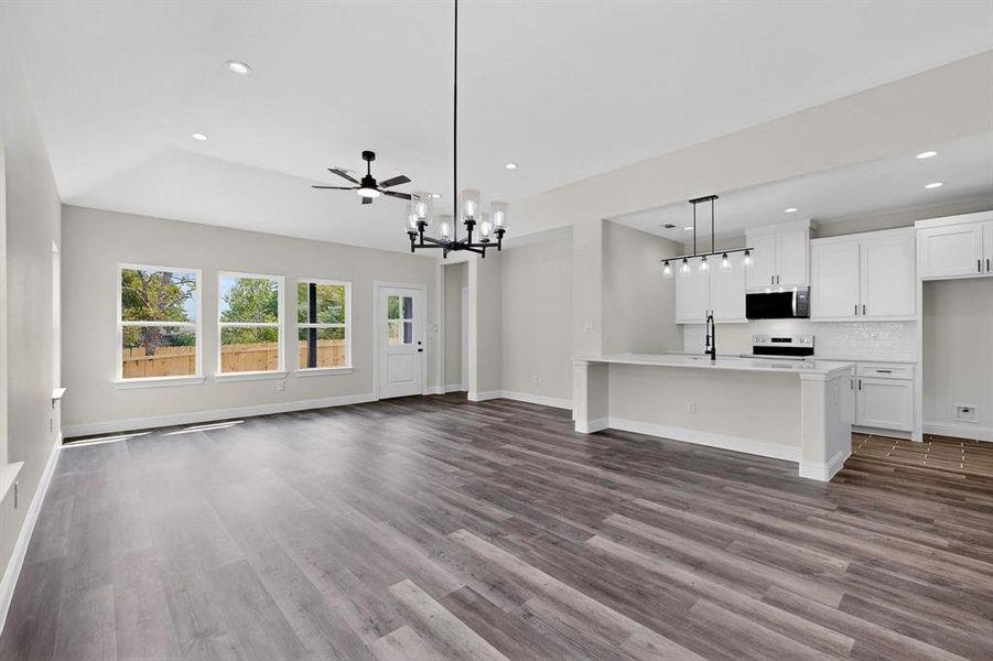 Unfurnished living room with dark wood finished floors, recessed lighting, a chandelier, and ceiling fan Unfurnished living room with dark wood finished floors, recessed lighting, a chandelier, and ceiling fan