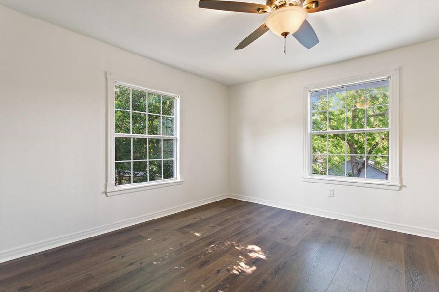 Unfurnished room with healthy amount of natural light, baseboards, and dark wood finished floors