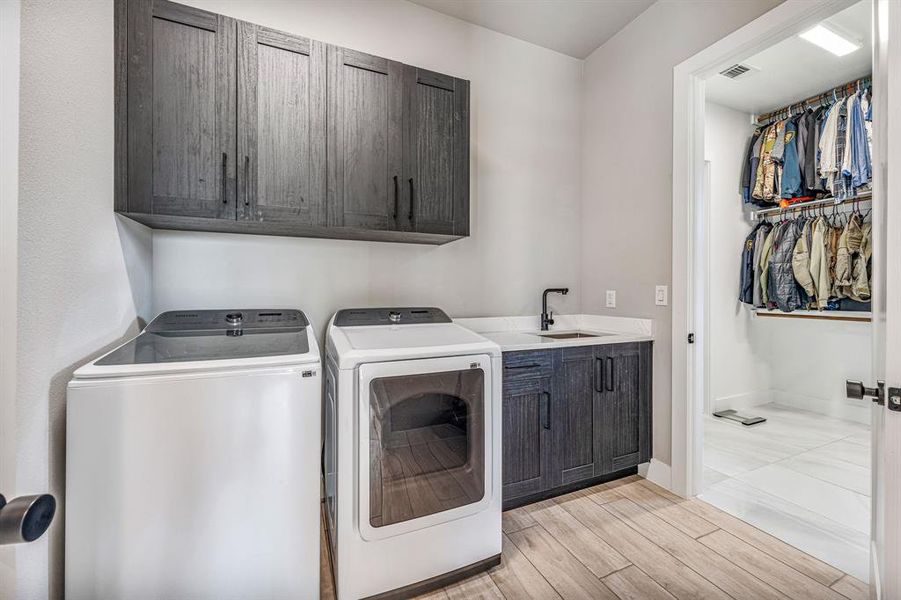 Washroom with cabinet space, light wood-style floors, and washer and clothes dryer