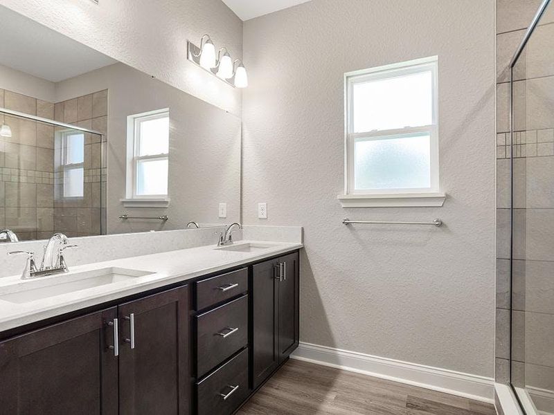 Your suite is complete with a private en-suite bath with a tiled shower, linen closet, and a closeted toilet - Monroe 55+ by Highland Homes