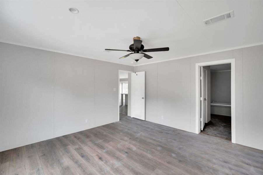 Spacious room featuring wood-finish flooring, light gray wall panels, and white trim