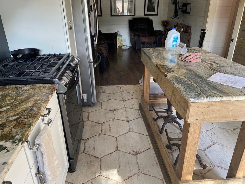 Kitchen featuring appliances with stainless steel finishes, dark stone counters, light wood finished floors, wooden walls, and a breakfast bar area